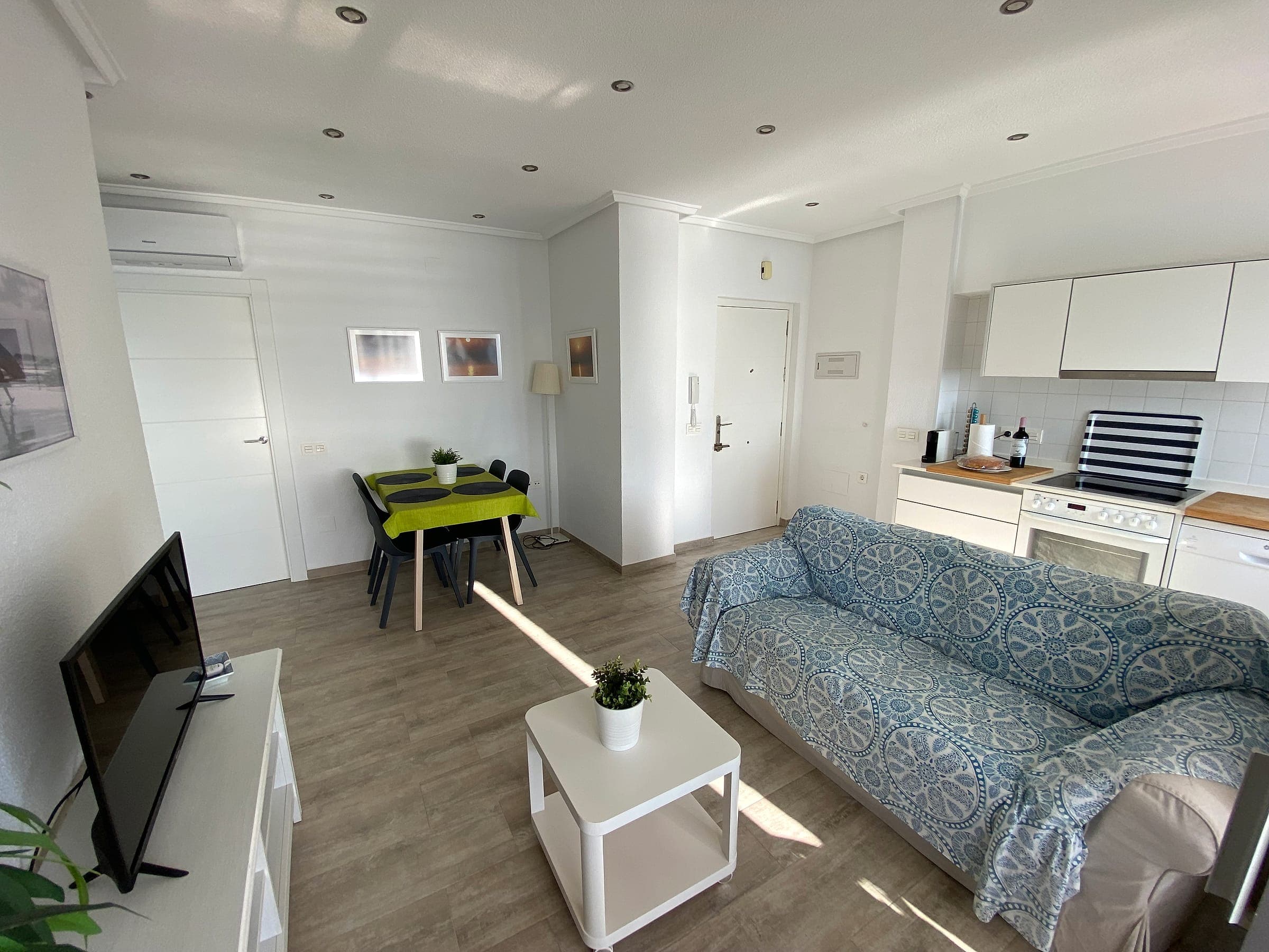 Salón con sofá, televisión y mesa de comedor para cuatro personas