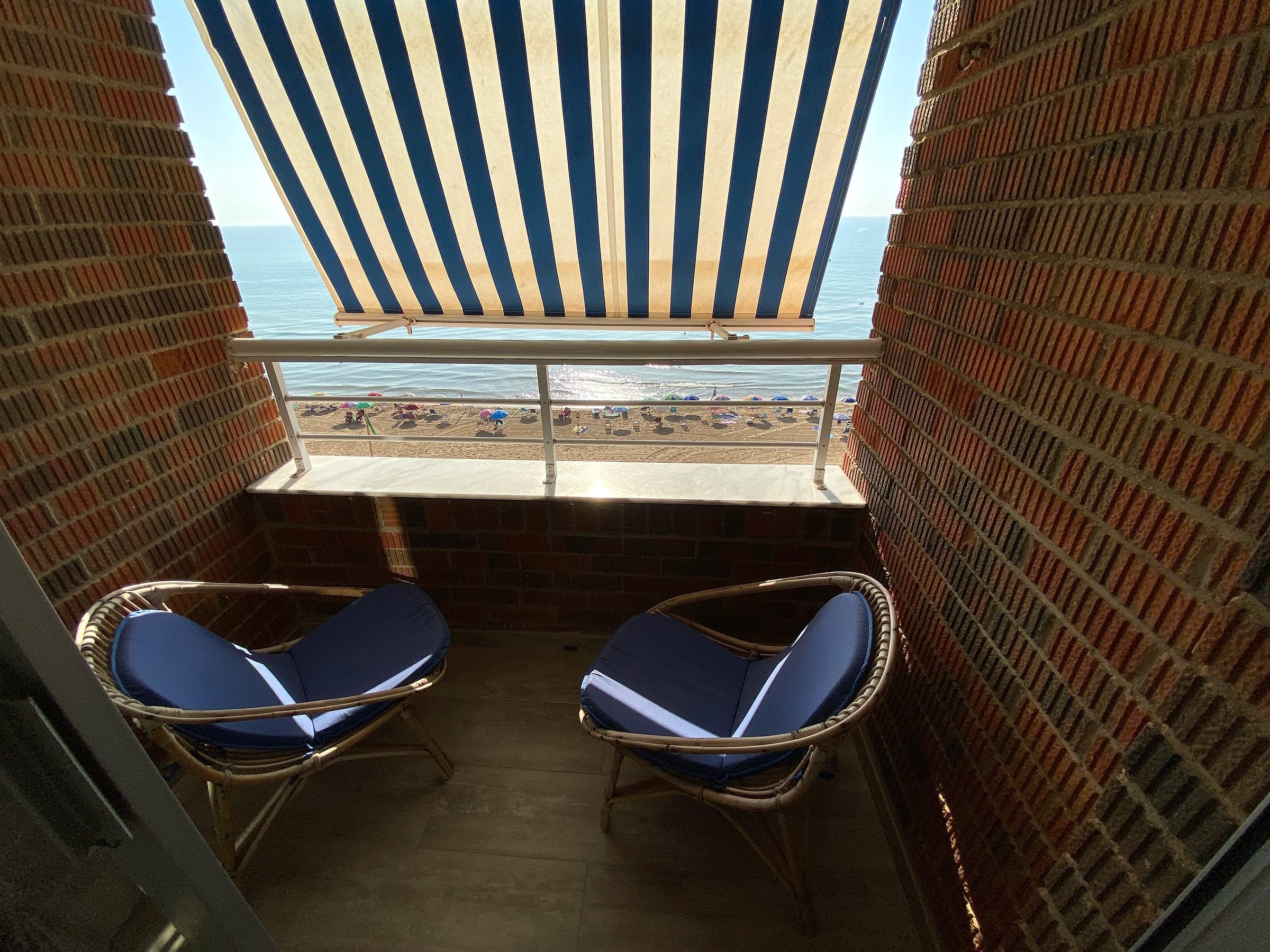 Terraza con dos sillones y toldo, frente a la playa